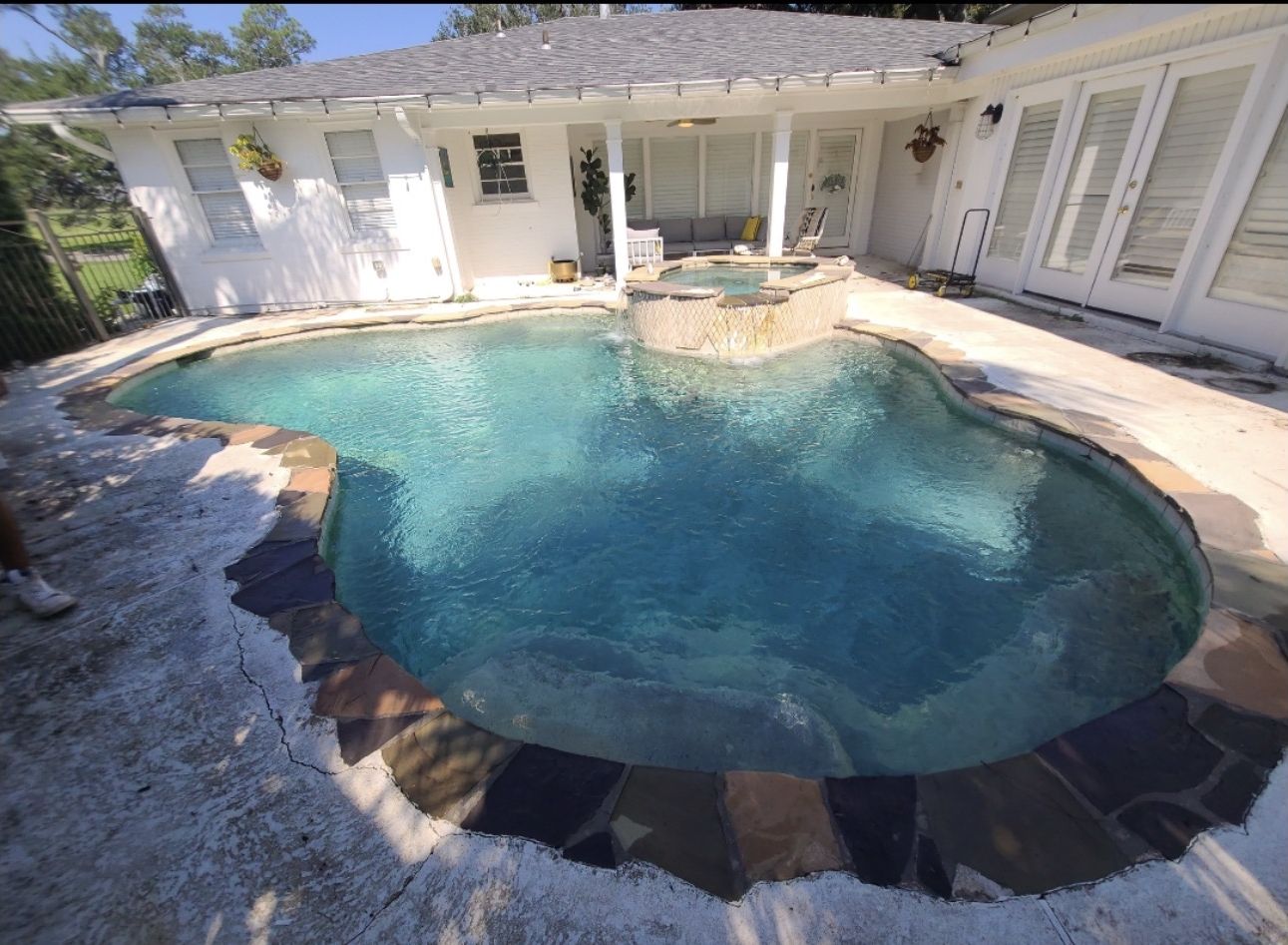 Before: freeform pool with a cracked, peeling deck, worn stone edge, and chipped spa tile