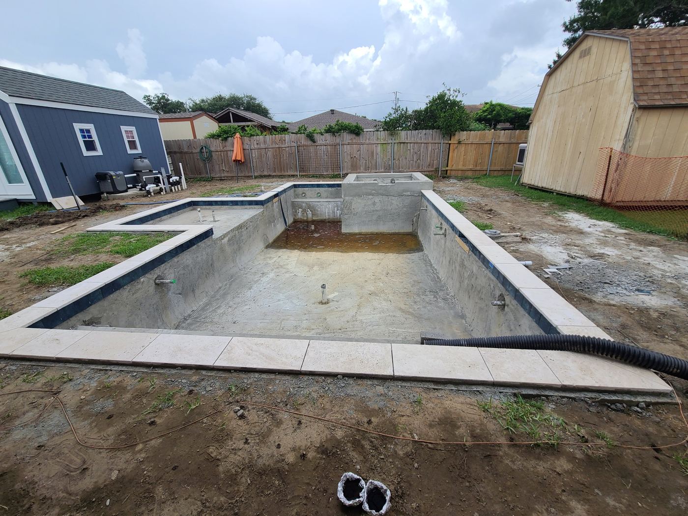 Step 9 of 14, Tile & coping: Waterline tile and travertine coping set around the edge.